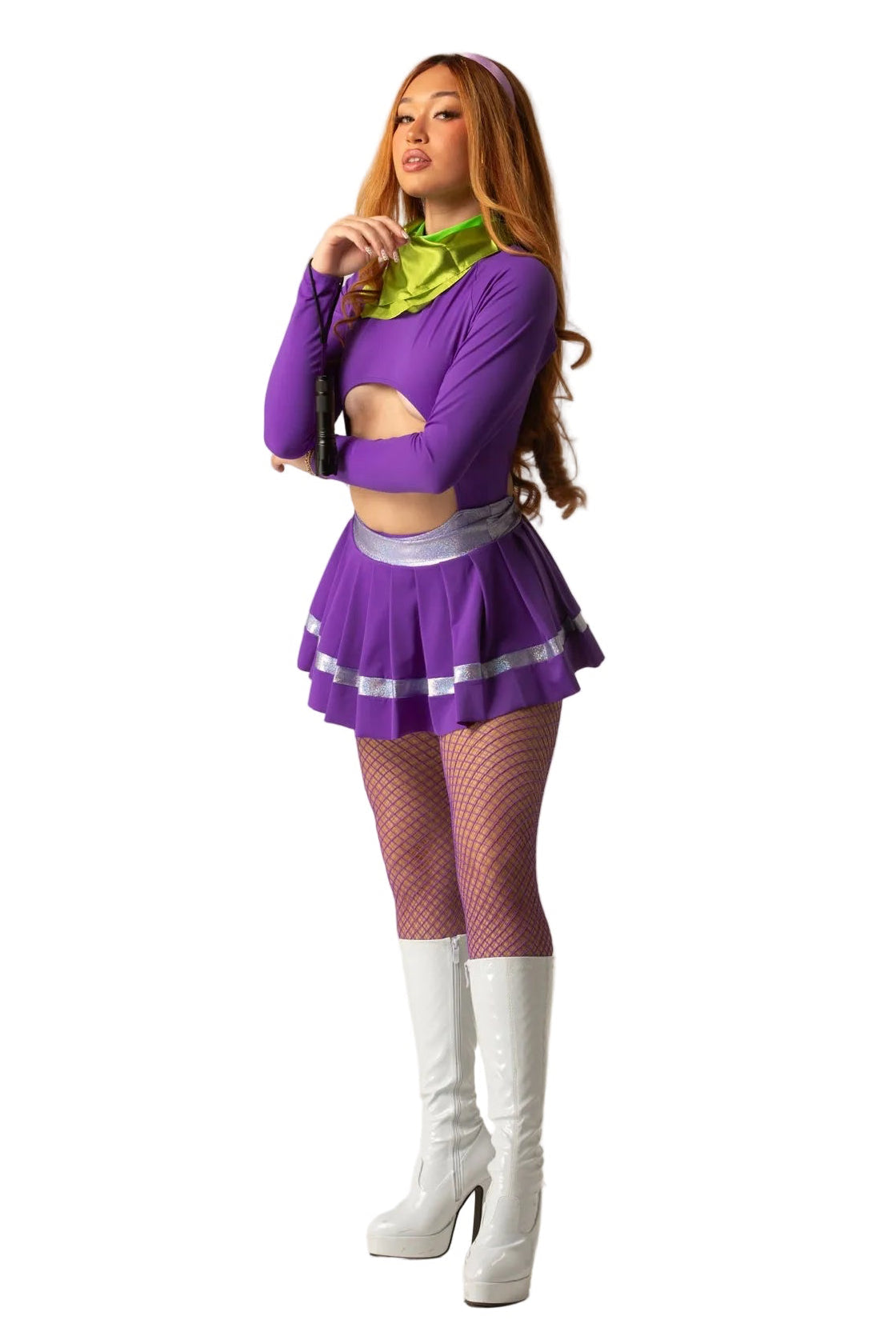 A woman modeling a purple and lime green costume outfit consisting of a long-sleeve crop top, pleated mini skirt with silver trim, fishnet tights, and white knee-high boots, against a plain beige studio background.